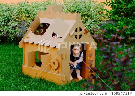 Children are playing in cardboard kid house. Child having fun outdoors. Children are playing in cardboard kid house. Child having fun outdoors. 109547117