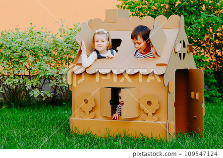 Children are playing in cardboard kid house. Child having fun outdoors. 109547124
