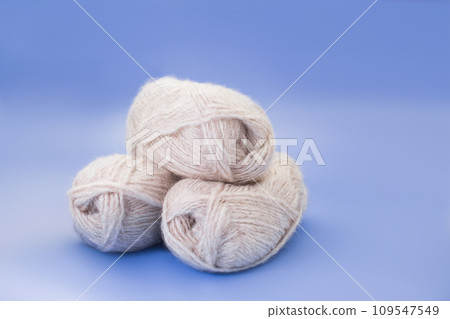 Yarn of gray wool in slide and wooden white fluffy deer on blue background. Concept of sewing, knitting, handmade. Copy space Yarn of gray wool in slide and wooden white fluffy deer on blue background. Concept of sewing, knitting, handmade. Copy space 109547549