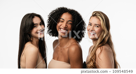 Female models of different ages celebrating their natural bodies in a studio. Three confident and happy women smiling cheerfully. Women standing together against a studio background. 109548549