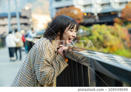 A woman crossing a bridge A woman standing in the autumn leaves A woman crossing a bridge A woman standing in the autumn leaves 109549040
