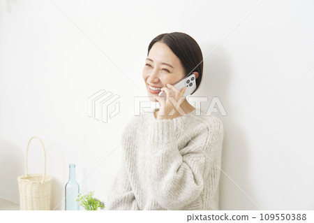 Middle-aged woman talking on smartphone at home Middle-aged woman talking on smartphone at home 109550388
