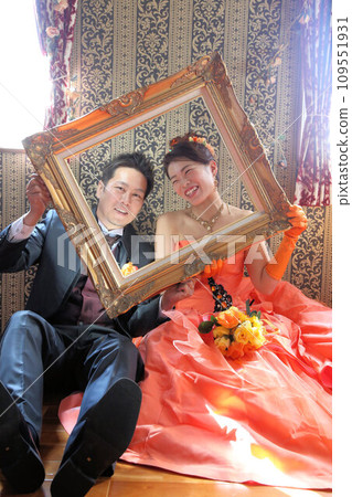 The bride in an orange wedding color dress, the groom in a tuxedo, and the bride in a wedding cocktail dress 109551931
