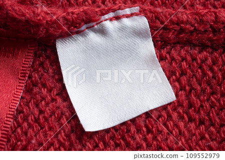 Blank laundry care clothes label on red knitted fabric texture background Blank laundry care clothes label on red knitted fabric texture background 109552979