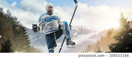 Shout for victory. Very emotional hockey player with stick and puck in his hands. Hockey player on an outdoor skating rink in the forest. Sports emotions Shout for victory. Very emotional hockey player with stick and puck in his hands. Hockey player on an outdoor skating rink in the forest. Sports emotions 109553166