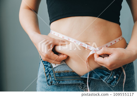 fat woman, fat belly, chubby, obese woman hand holding excessive belly fat with measure tape, woman diet lifestyle concept 109555117