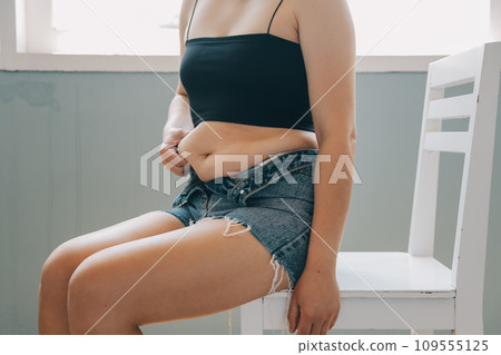 fat woman, fat belly, chubby, obese woman hand holding excessive belly fat with measure tape, woman diet lifestyle concept 109555125