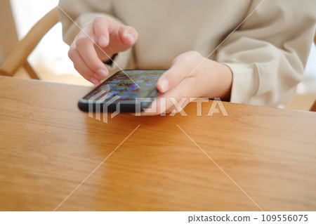 Hands of an elementary school girl using a smartphone Hands of an elementary school girl using a smartphone 109556075