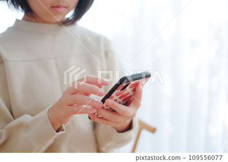 Hands of an elementary school girl using a smartphone Hands of an elementary school girl using a smartphone 109556077