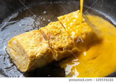 玉子燒蛋捆綁,烹飪場景。將打好的雞蛋加入到用高湯煮好的玉子燒中。 玉子燒蛋捆綁,烹飪場景。將打好的雞蛋加入到用高湯煮好的玉子燒中。 109559288