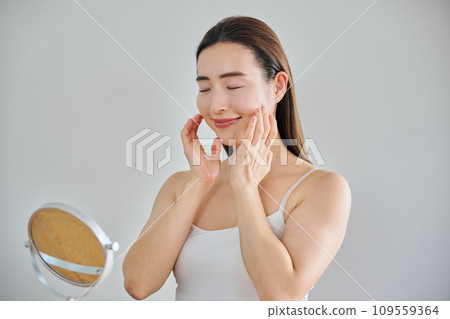 A woman in her 30s taking care of her skin by massaging her face 109559364