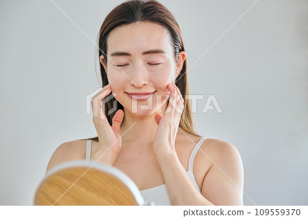 A woman in her 30s taking care of her skin by massaging her face 109559370