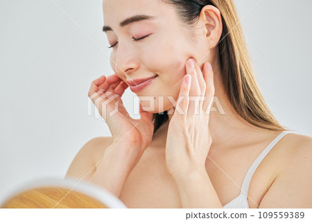 A woman in her 30s taking care of her skin by massaging her face A woman in her 30s taking care of her skin by massaging her face 109559389
