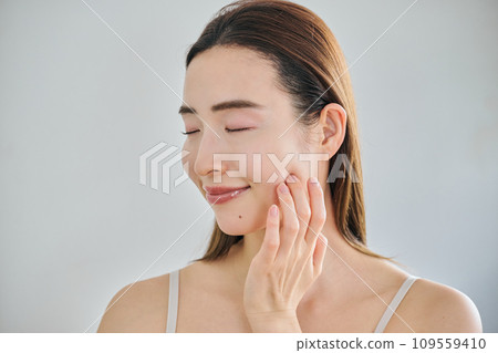 A woman in her 30s taking care of her skin by massaging her face 109559410