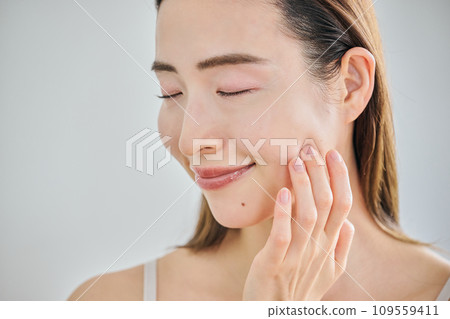 A woman in her 30s taking care of her skin by massaging her face 109559411