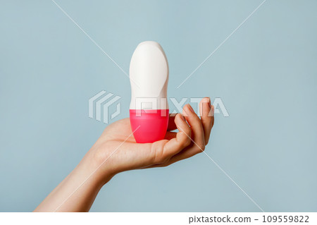 Female hand holds body deodorant on blue background, copy space 109559822