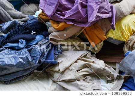 garbage dump with a lot of clothes on the street, environmental pollution problem excessive consumption 109559833