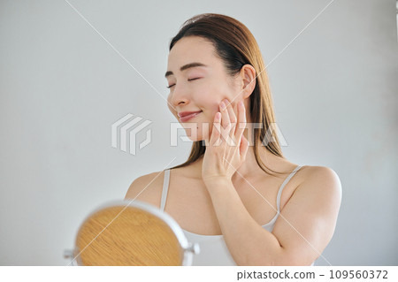 A woman in her 30s taking care of her skin by massaging her face A woman in her 30s taking care of her skin by massaging her face 109560372