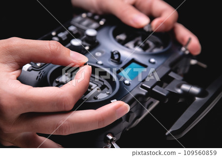 female hands holding sticks on the remote control of a drone, close-up, indoors female hands holding sticks on the remote control of a drone, close-up, indoors 109560859