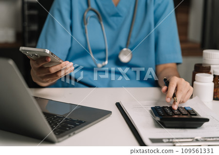 Doctor use a service fee calculator to save money on health insurance, drug cost concept. Doctor use a service fee calculator to save money on health insurance, drug cost concept. 109561331