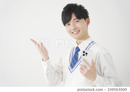 High school boy holding a smartphone and pointing to the left side with his palm, white background High school boy holding a smartphone and pointing to the left side with his palm, white background 109563000