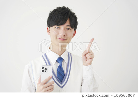 拿著智慧型手機並指向右側白色背景的高中男孩 109563007