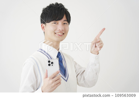 拿著智慧型手機並指向右側白色背景的高中男孩 109563009