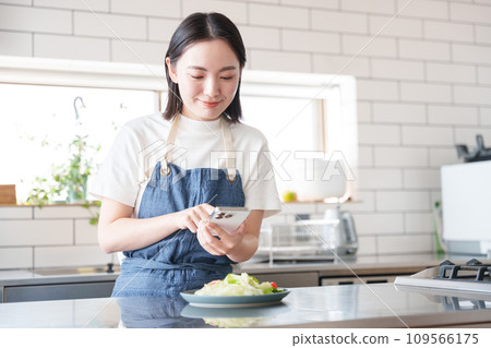 A woman taking pictures of food with a smartphone A woman taking pictures of food with a smartphone 109566175