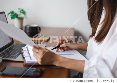 Businesswomen reading data on laptop and checking finance document while working in outside office 109566915
