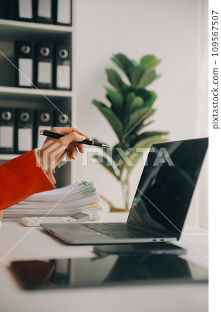 Attractive smiling young asian business woman work at home office, Asian woman working on laptop computer holding tablet. 109567507