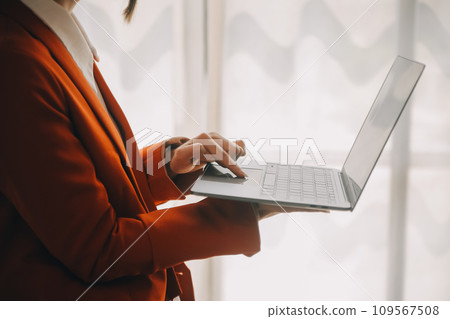 Attractive smiling young asian business woman work at home office, Asian woman working on laptop computer holding tablet. 109567508