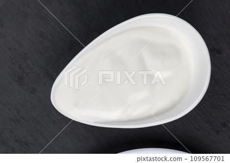creamy sour cream in a white glass bowl on a black board 109567701