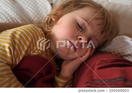 Peaceful adorable baby sleeping on a bed at home. Slumbering little child. Two year old girl sleeps peaceful at domestic room interior background. Serene dream. Cute face close up. Deep kid slumber Peaceful adorable baby sleeping on a bed at home. Slumbering little child. Two year old girl sleeps peaceful at domestic room interior background. Serene dream. Cute face close up. Deep kid slumber 109569003