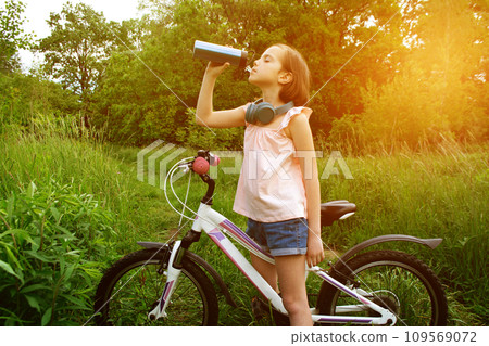 Little cute girl riding a bike with basket full of flowers. Little cute girl riding a bike with basket full of flowers. 109569072