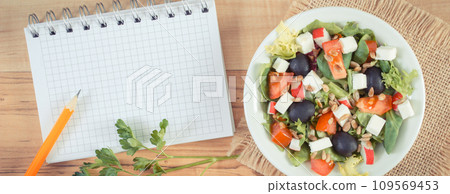 Fresh greek salad with feta cheese and notepad. Healthy nutrition Fresh greek salad with feta cheese and notepad. Healthy nutrition 109569453