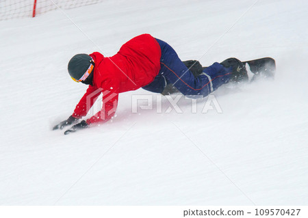 Person in a red jacket and black helmet riding a snowboard. Selective focus Person in a red jacket and black helmet riding a snowboard. Selective focus 109570427