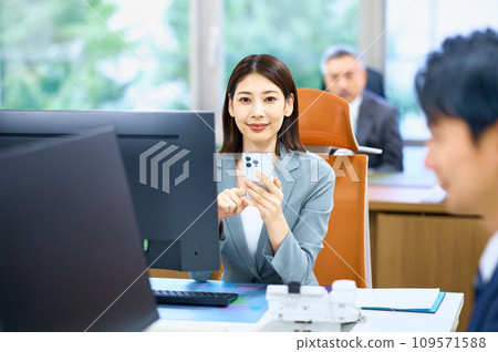 一位年輕的女商人在辦公室看智能手機 一位年輕的女商人在辦公室看智能手機 109571588
