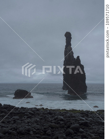 View of rocky formation Ilheus da Ribeira da Janela at rocky beach on the north coast of Madeira island Portugal near Porto Moniz. Three high rocks in the sea. Monochromatic, rainy cloudy day 109571710