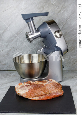 Electric eat grinder and fresh meat on kitchen table. Preparation of minced meat Electric eat grinder and fresh meat on kitchen table. Preparation of minced meat 109572251