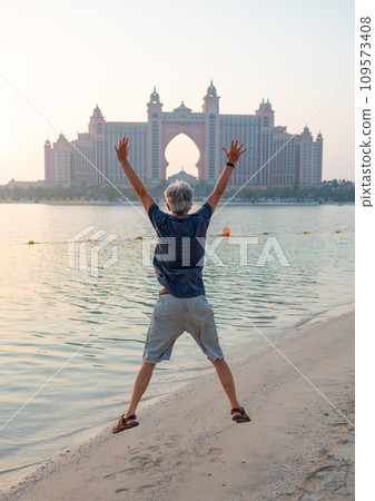 Senior visiting Palm Jumeirah in Dubai standing on the public beach 109573408