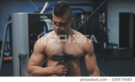 Muscular arab man training with dumbbells in the gym. 109574980