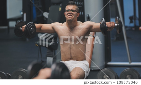 Arab male athlete improves his shoulders with dumbbell breeding. 109575046