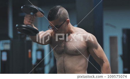 Muscular arab man training with dumbbells in the gym. 109575074