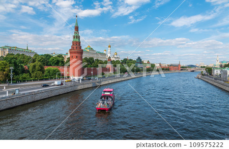 View of Kremlin with Vodovzvodnaya tower, Grand Kremlin Palace from repaired Bolshoy Kamenny Bridge in Moscow city on sunny summer day. Cruise ship sails on the Moscow river 109575222