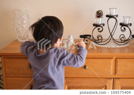 一個4歲的男孩對客廳板上的裝飾品很感興趣。 一個4歲的男孩對客廳板上的裝飾品很感興趣。 109575404