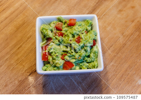 Bowl of guacamole on a wooden table 109575487