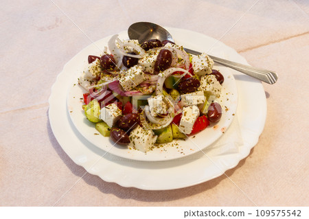 Greek salad with fresh vegetables, feta cheese and olives on a table 109575542