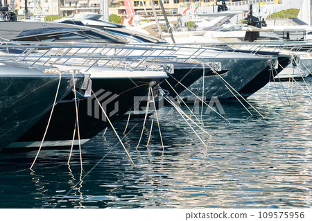 Sun glare on glossy board boats, azure water, tranquillity in port Hercules, bows of moored boats at sunny day, megayachts, Monaco, Monte-Carlo Sun glare on glossy board boats, azure water, tranquillity in port Hercules, bows of moored boats at sunny day, megayachts, Monaco, Monte-Carlo 109575956