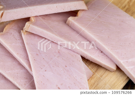 slicing a finished piece of ham into small pieces 109576266