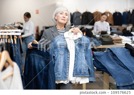 Elderly woman choosing denim jacket in store Elderly woman choosing denim jacket in store 109576625